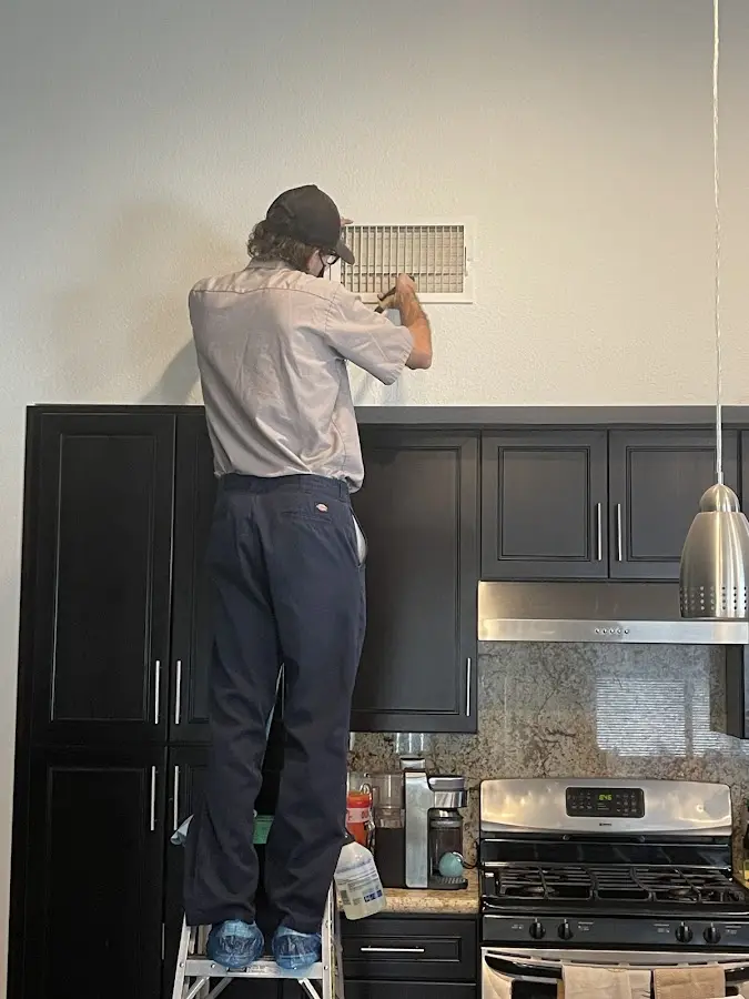 Technician inspecting an air vent during HVAC service in Lely Resort
